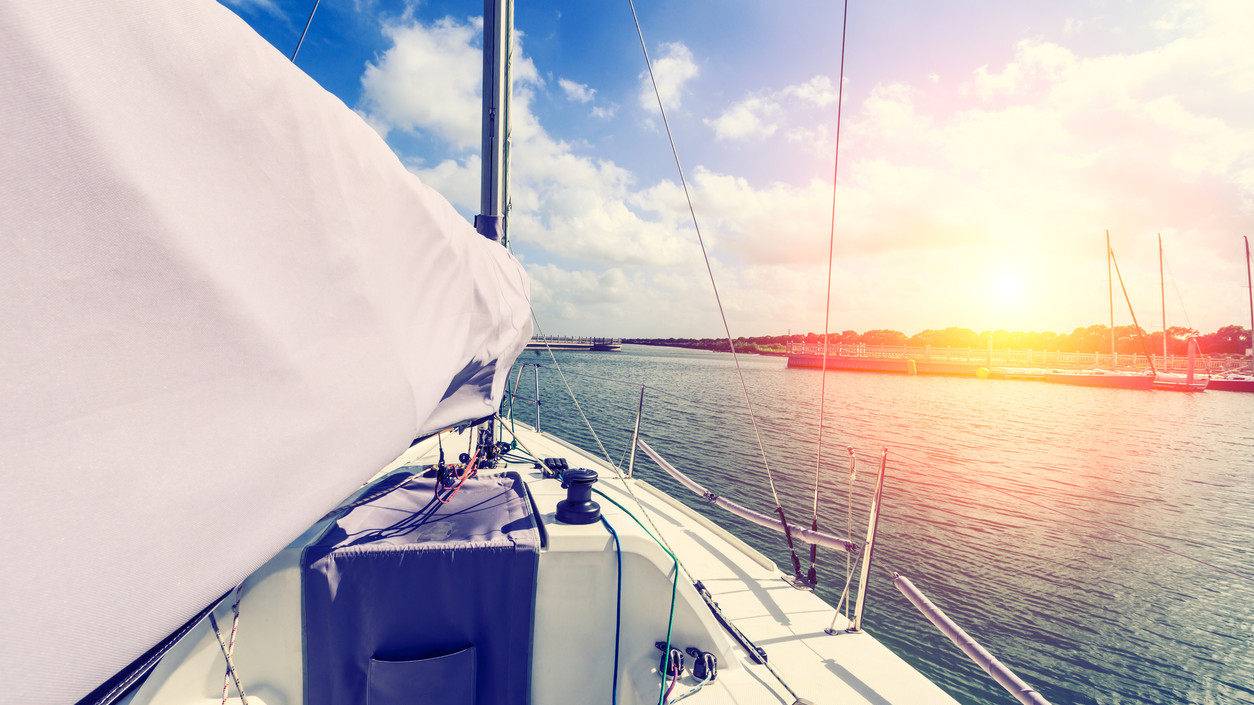 white sailboat is ready to sail out of the harbor