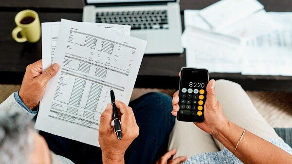 Two people reviewing statements, one holding a pen, the other holding a calculator.