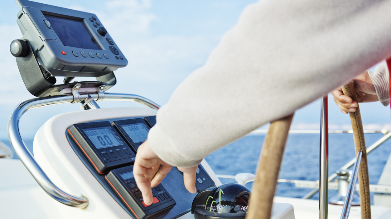 skipper adjusting navigating yacht's auto pilot