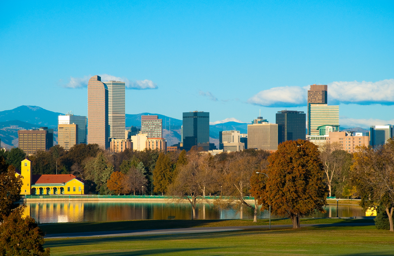 Denver downtown skyline in Autumn w/ City Park and lake in the foreground and the Rocky Mountains in the background.