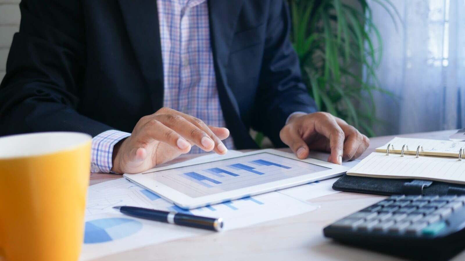 man looking at graphs, finance, calculator on ipad, tablet