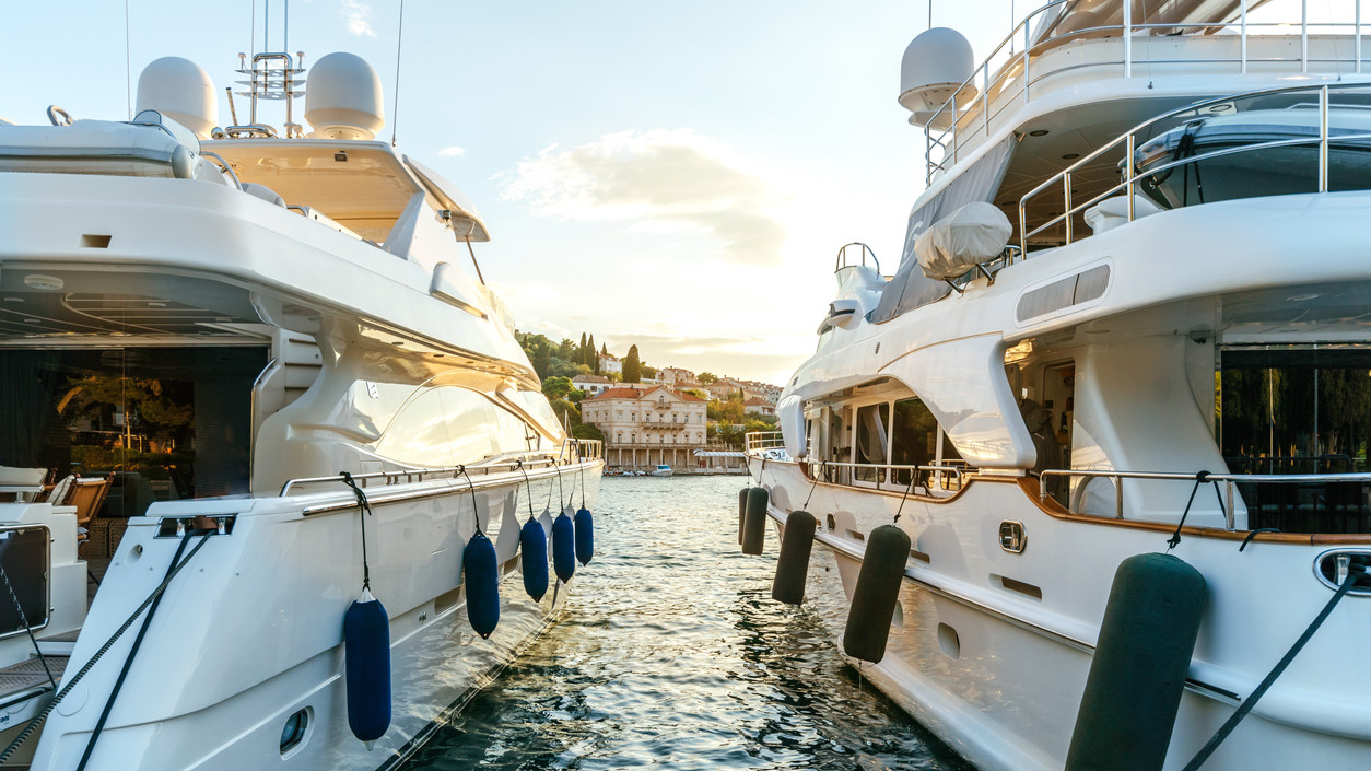 Large luxury yachts moored in the port of a tourist Mediterranean city in sunset light