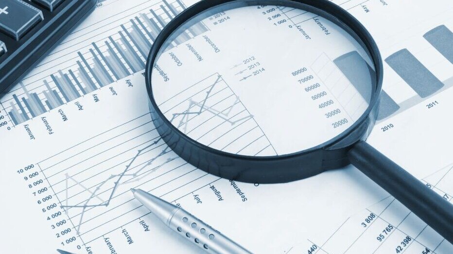 Business concept with magnifying glass, calculator, pen, pencils and financial documents