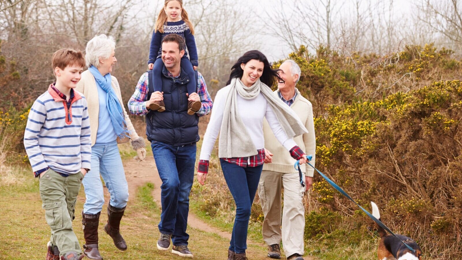 An extended family taking a walk outdoors, with their dog.