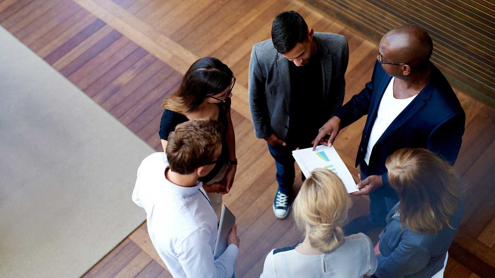 Aerial view of 6 co-workers reviewing a report.