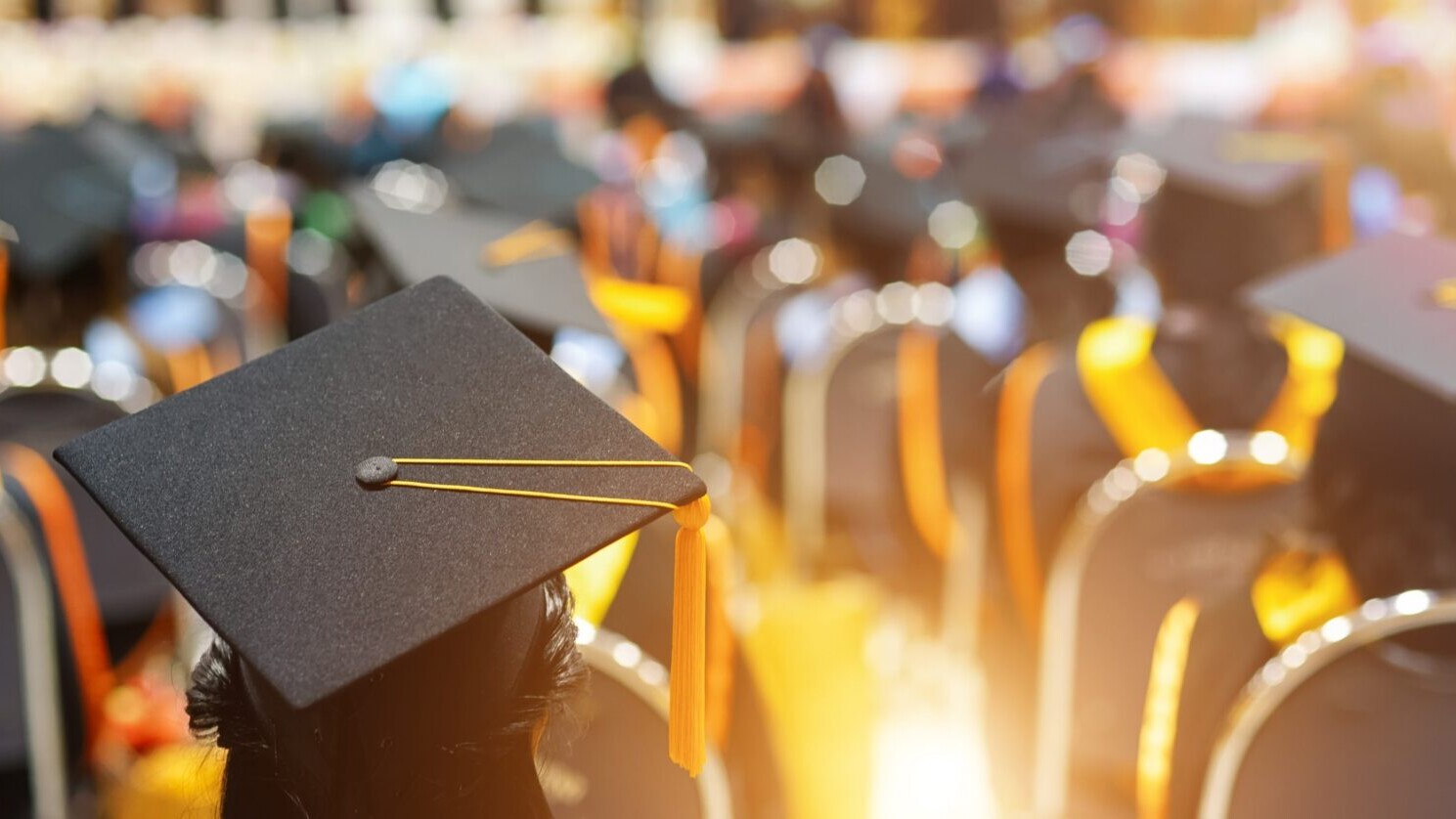 Rows of graduates, with a close-up of a cap.