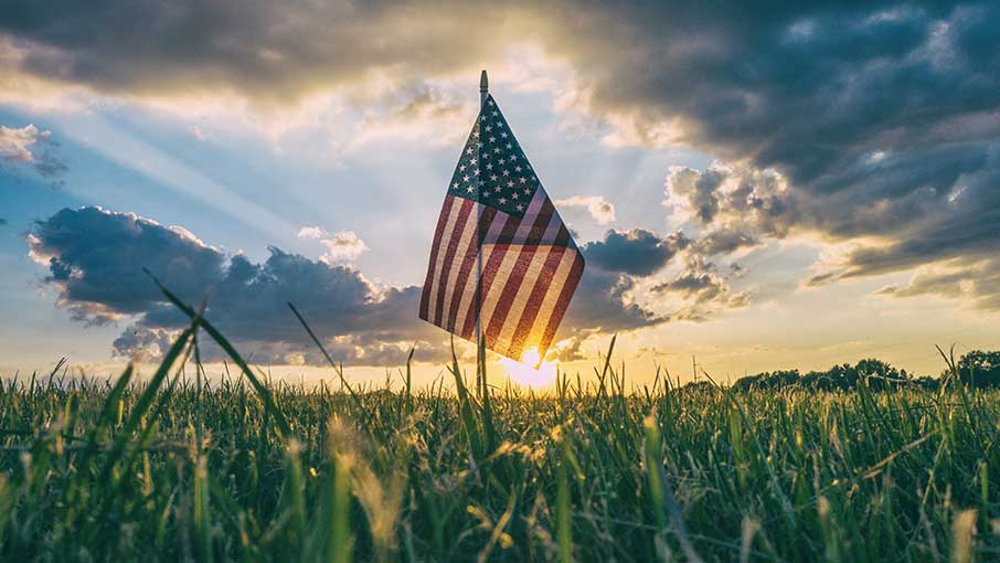 American flag at dawn on grass.