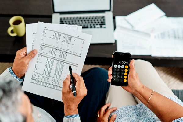 Two people reviewing statements, one holding a pen, the other holding a calculator.