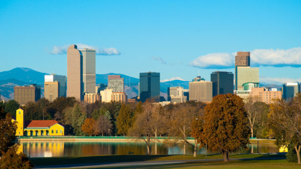 Denver downtown skyline in Autumn w/ City Park and lake in the foreground and the Rocky Mountains in the background.