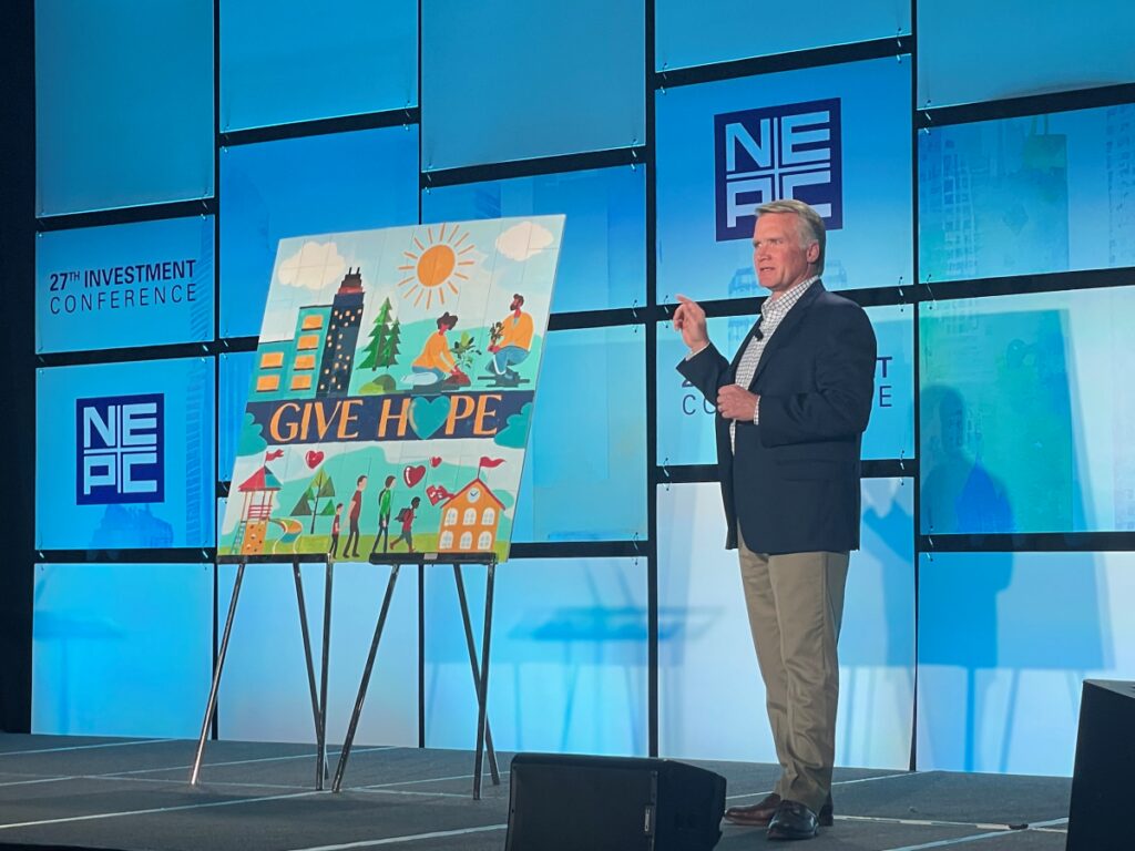 Steve Charlton on stage at NEPC's annual Investment Conference presenting mural to donate to Ronald McDonald House Boston Harbor