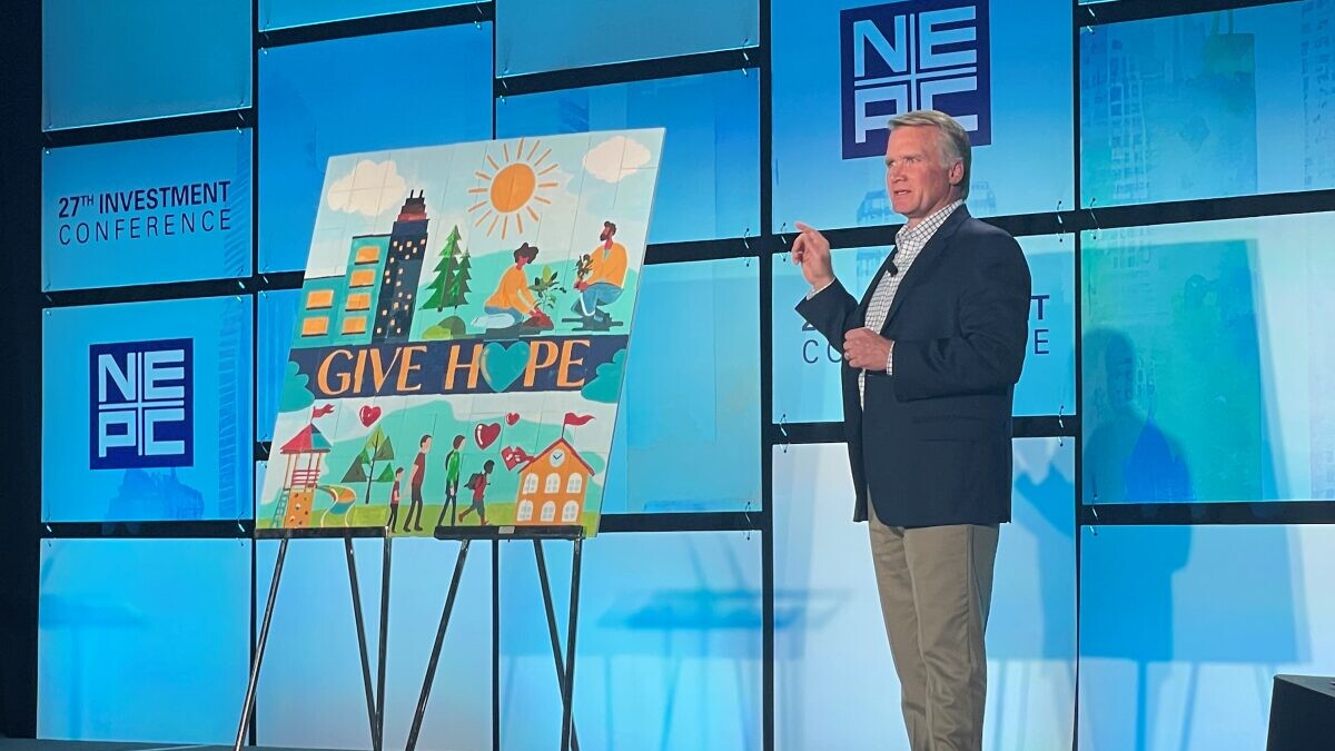 Steve Charlton on stage at NEPC's annual Investment Conference presenting mural to donate to Ronald McDonald House Boston Harbor