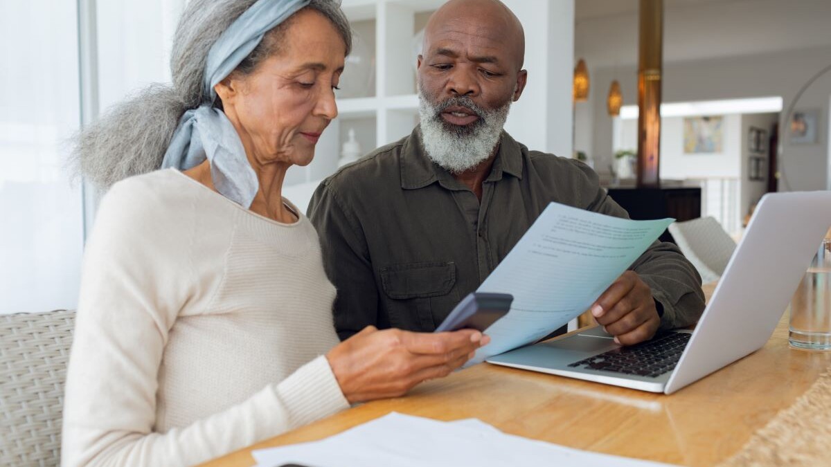 Couple discussing papers and using laptop inside a room