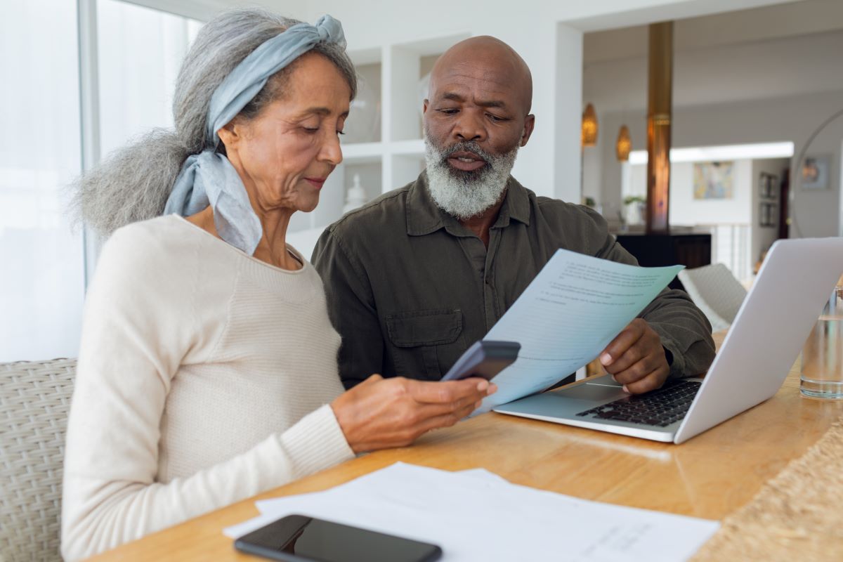 Couple discussing papers and using laptop inside a room