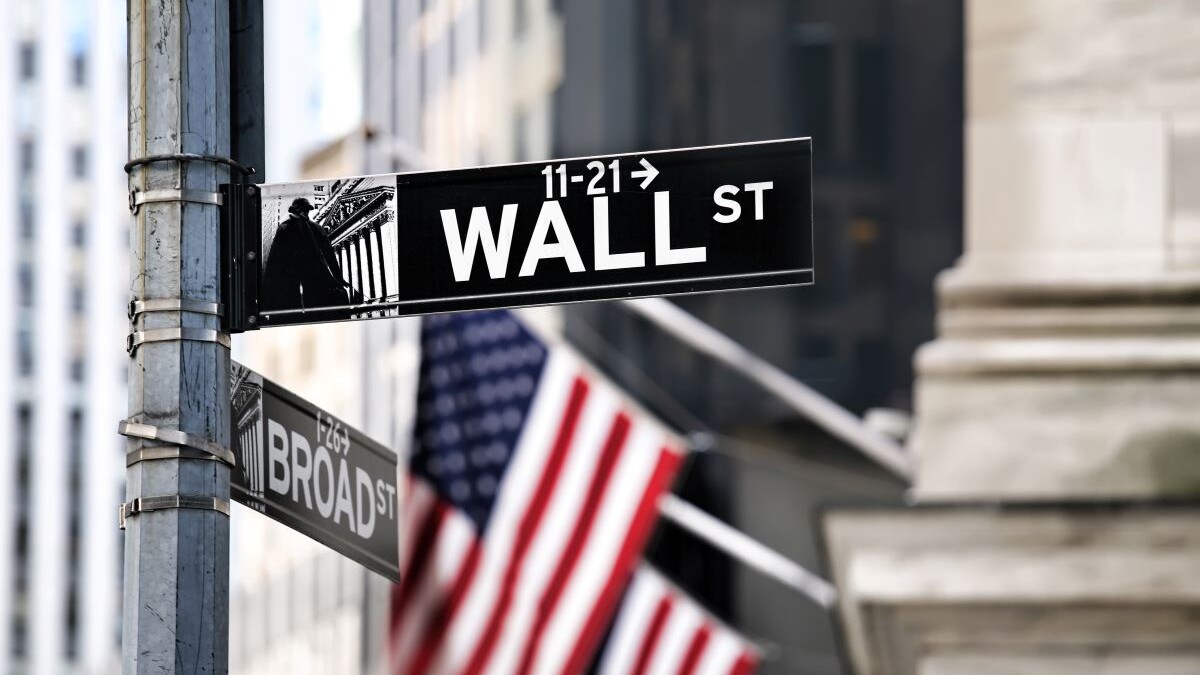 image of Wall Street's street sign with american flags in the background