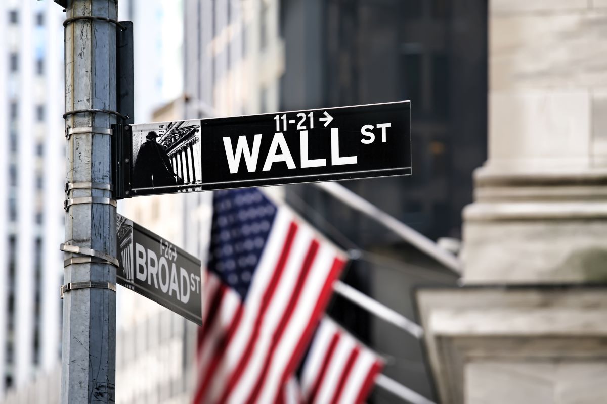 image of Wall Street's street sign with american flags in the background