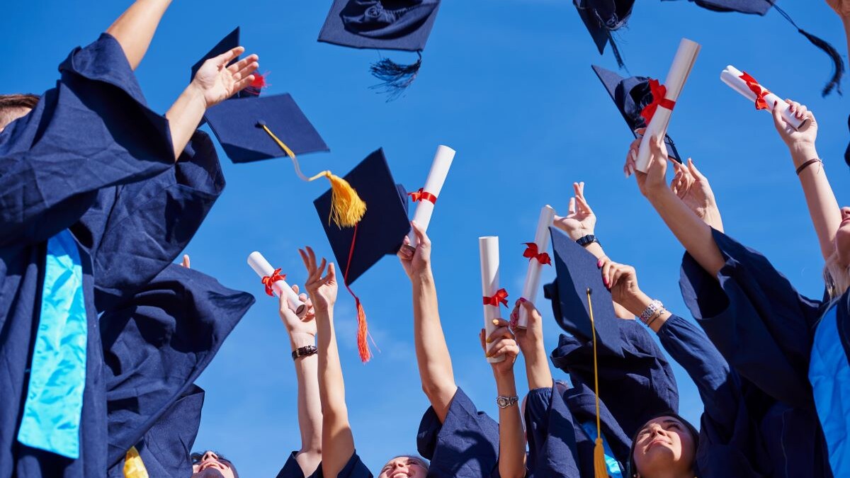 Image of graduates tossing caps and diplomas into the air