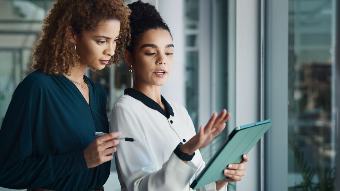 two women having a conversation while looking at an ipad