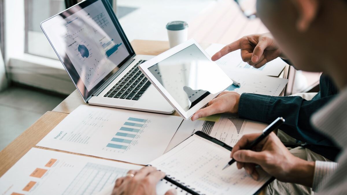 Business partnership coworkers using a tablet to analysis graph company financial budget report and cost work progress and planning for future in office room.