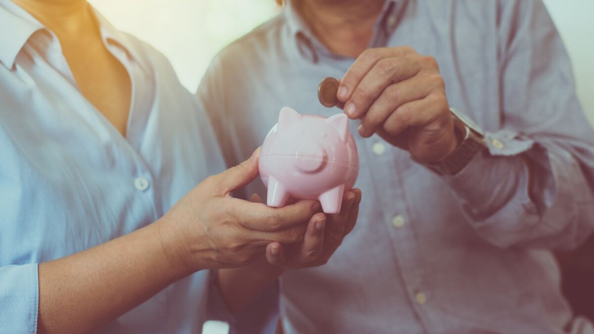Senior couple hands putting coin to piggy bank for retirement together, Saving money concept