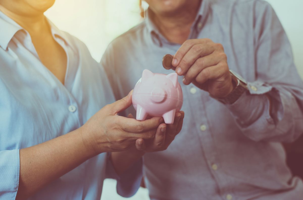 Senior couple hands putting coin to piggy bank for retirement together, Saving money concept