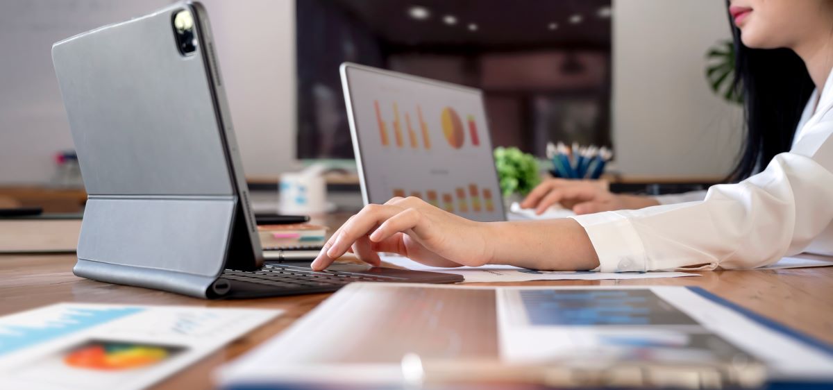 Businesswoman working at office with document on her desk, doing planning analyzing the financial report, business plan investment, finance analysis concept. Using laptop and tablet.