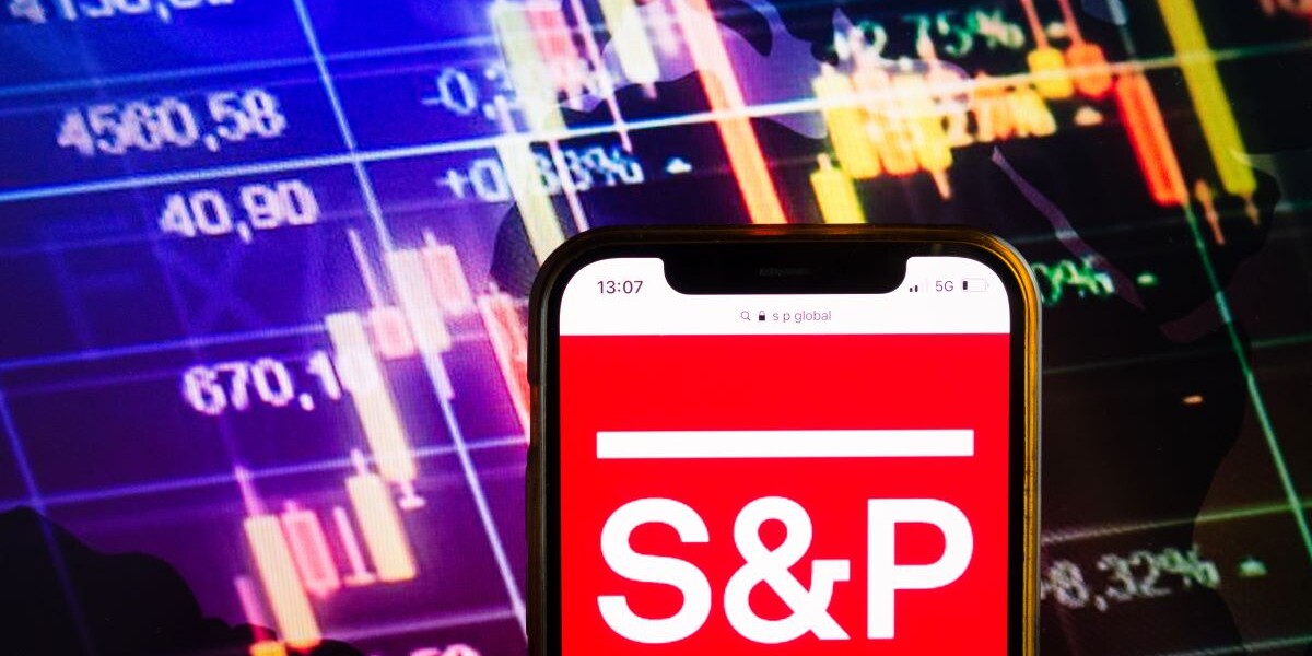 Smartphone displaying logo of S&P Global Ratings (previously Standard & Poor's) American credit rating agency on stock exchange chart background