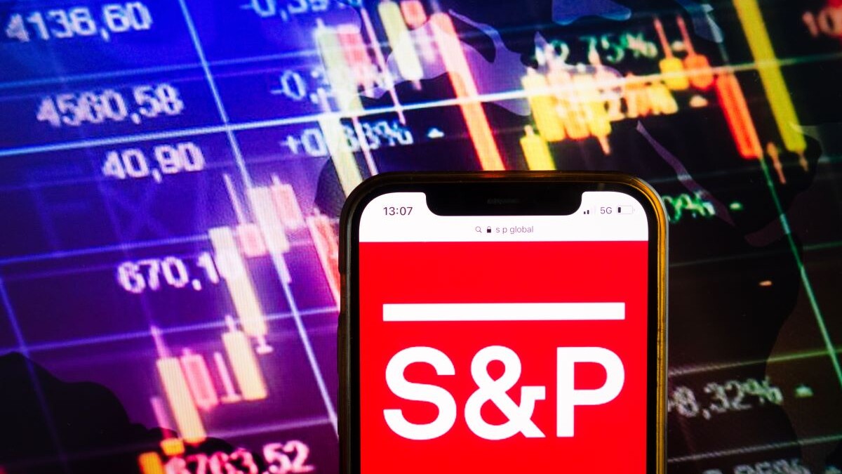 Smartphone displaying logo of S&P Global Ratings (previously Standard & Poor's) American credit rating agency on stock exchange chart background