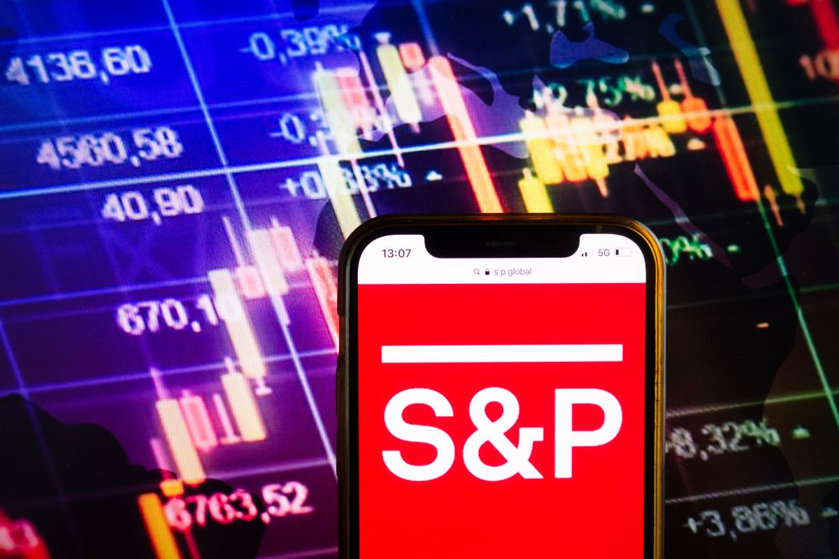 Smartphone displaying logo of S&P Global Ratings (previously Standard & Poor's) American credit rating agency on stock exchange chart background