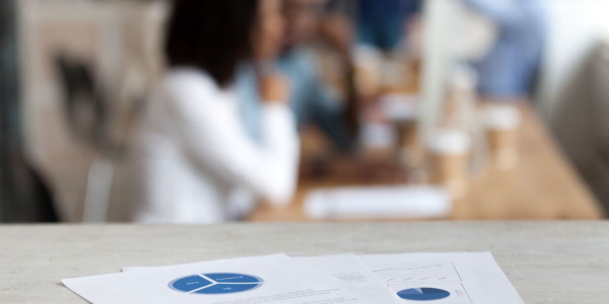 Document with financial report, pie diagram, marketing plan, paper business document on office table close up, employees, office workers working on background