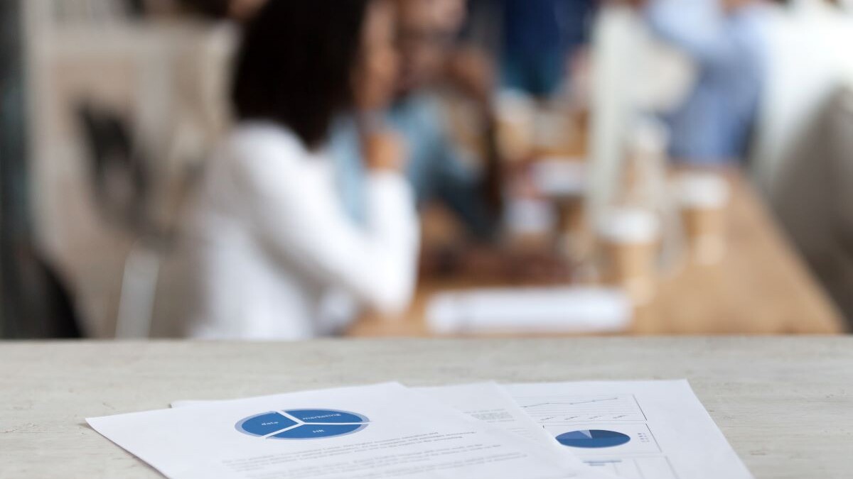 Document with financial report, pie diagram, marketing plan, paper business document on office table close up, employees, office workers working on background