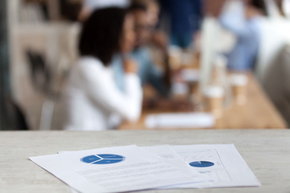 Document with financial report, pie diagram, marketing plan, paper business document on office table close up, employees, office workers working on background