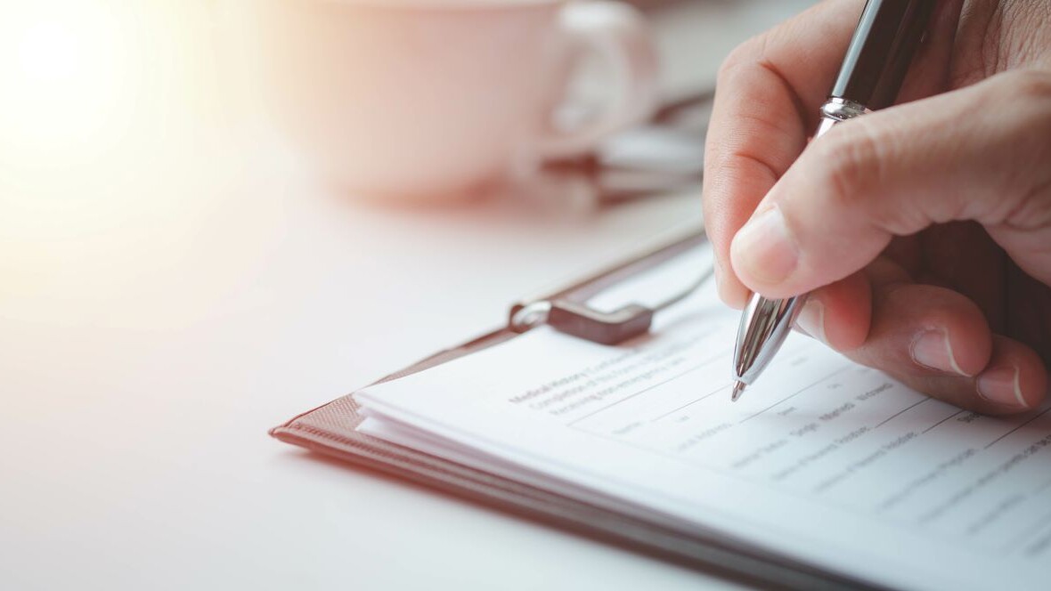 Close-up of Hand using writing pen with questionnaire or paperwork survey question filling in business company personal information form checklist document.