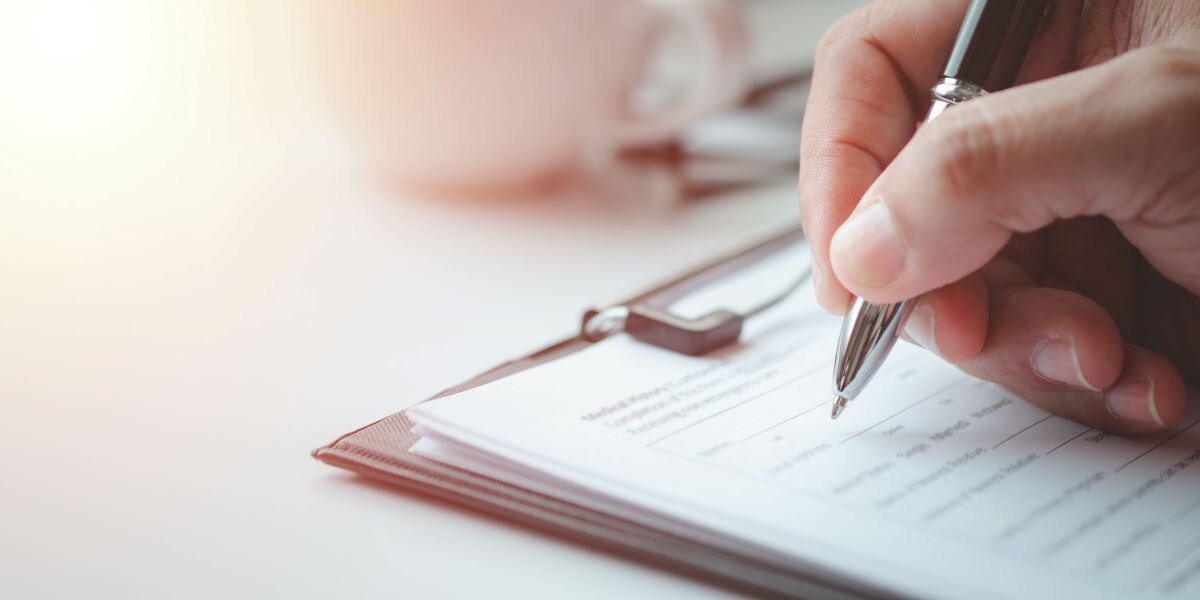 Close-up of Hand using writing pen with questionnaire or paperwork survey question filling in business company personal information form checklist document.