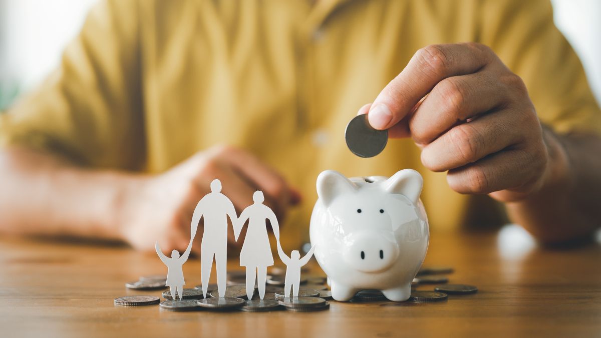 businessman putting coin on the piggybank and paper family on table, donation, saving, charity, family finance plan