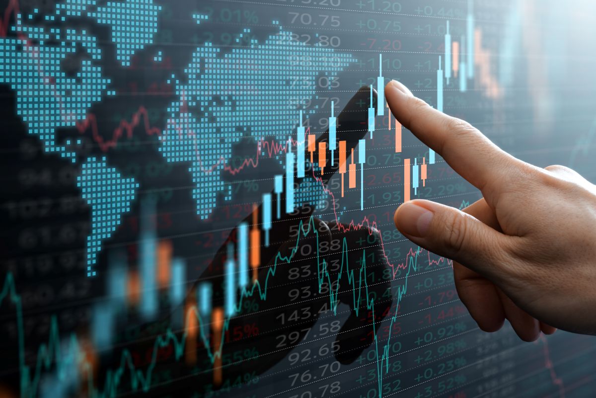 Graphs and world financial markets data. Investor pointing at the candlestick chart.