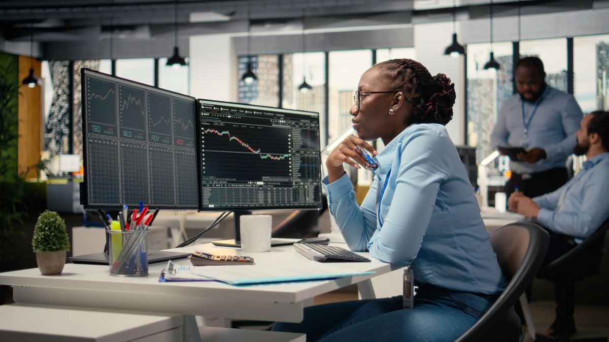 expert in office looking over candlestick charts on screen to assess stock market volatility.