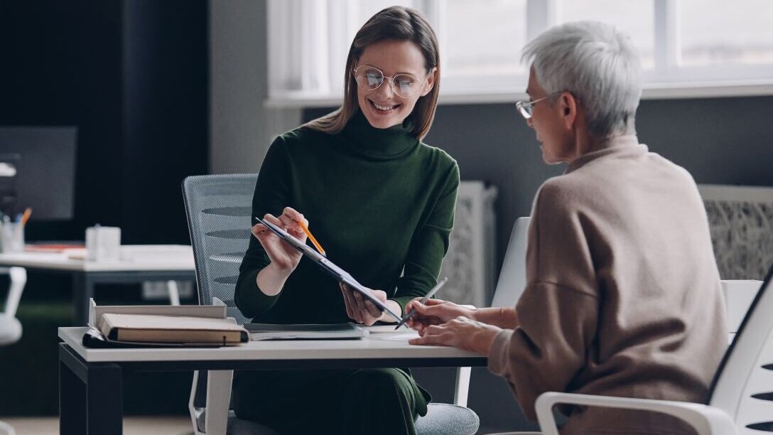 Senior woman discussing options with financial advisor while sitting in the office together