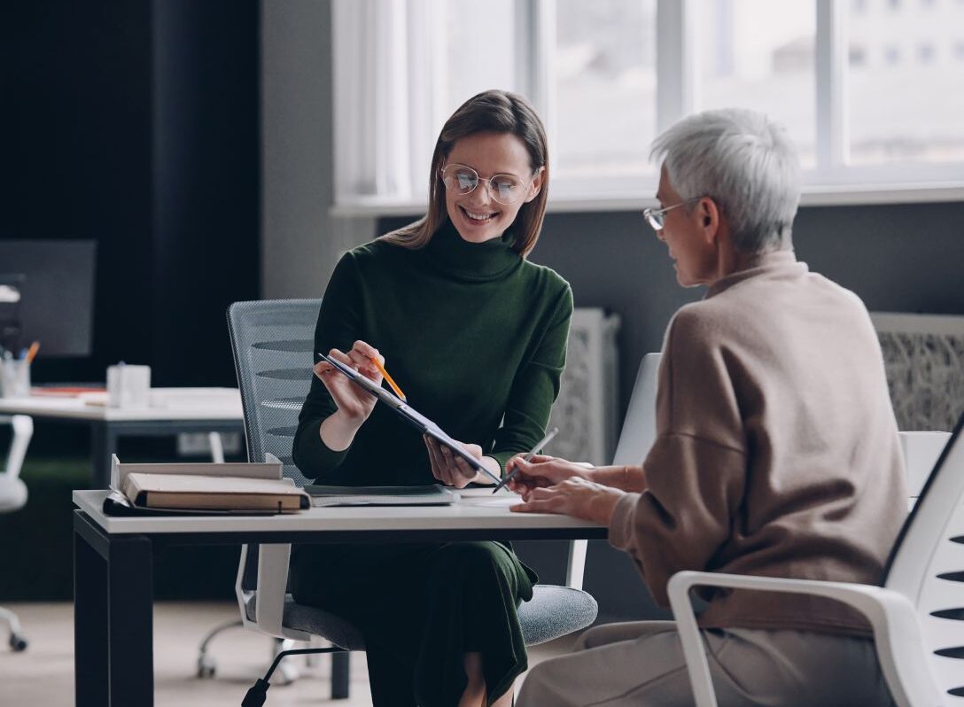 Senior woman discussing options with financial advisor while sitting in the office together