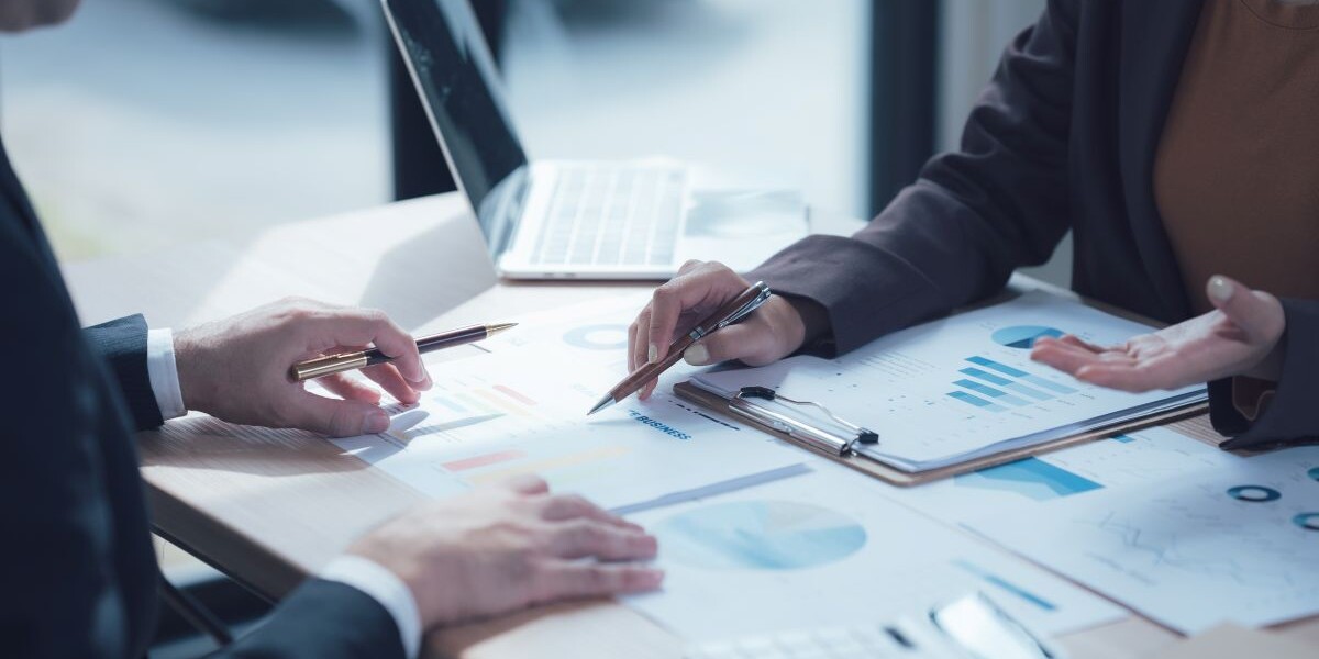 Analyzing the Numbers: A close-up shot of two professionals collaborating over a table scattered with charts, graphs, and a calculator.