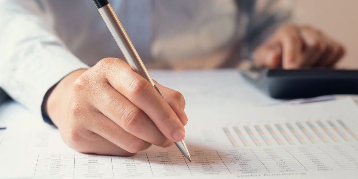 person writing with pen on paper with graphs