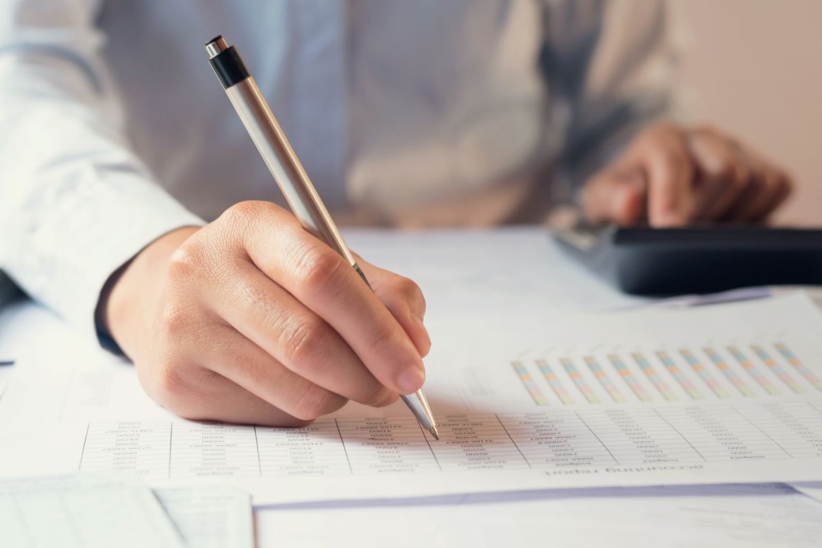 person writing with pen on paper with graphs