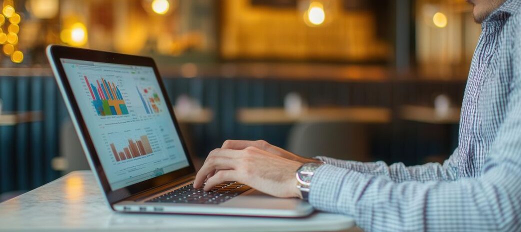 Financial analyst sitting in a private booth in a coworking cafe, reviewing expense trends on a high-end laptop