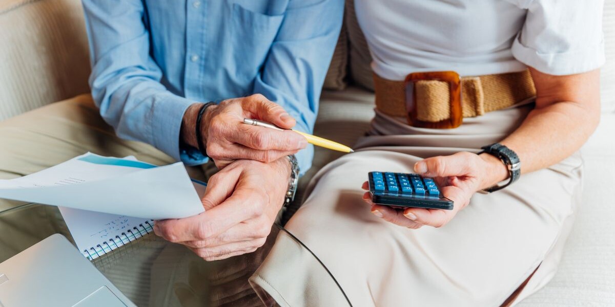 Elderly couple managing household finances and retirement planning, calculating expenses and reviewing bills on a laptop, stressing budget and financial consulting for seniors