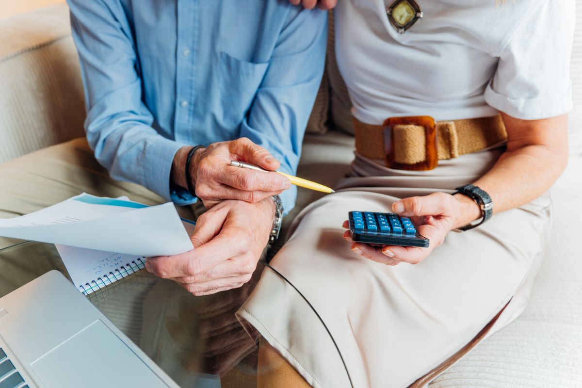 Elderly couple managing household finances and retirement planning, calculating expenses and reviewing bills on a laptop, stressing budget and financial consulting for seniors
