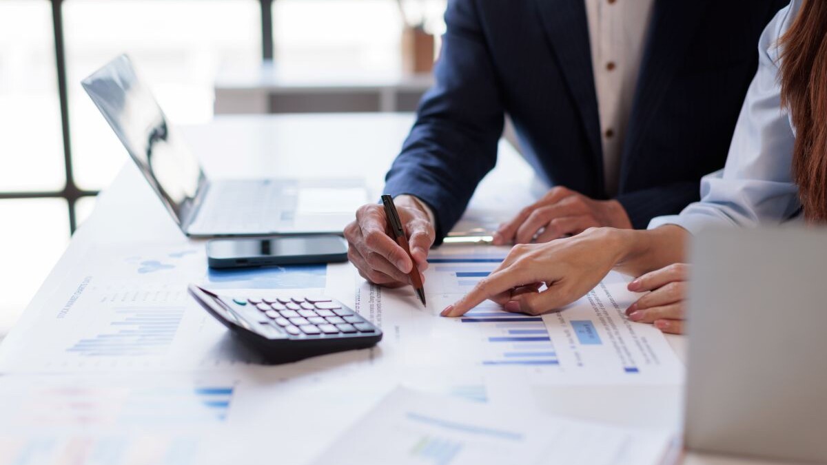 Hands and graphs on tablet screen for finance results, profit growth and budget review.